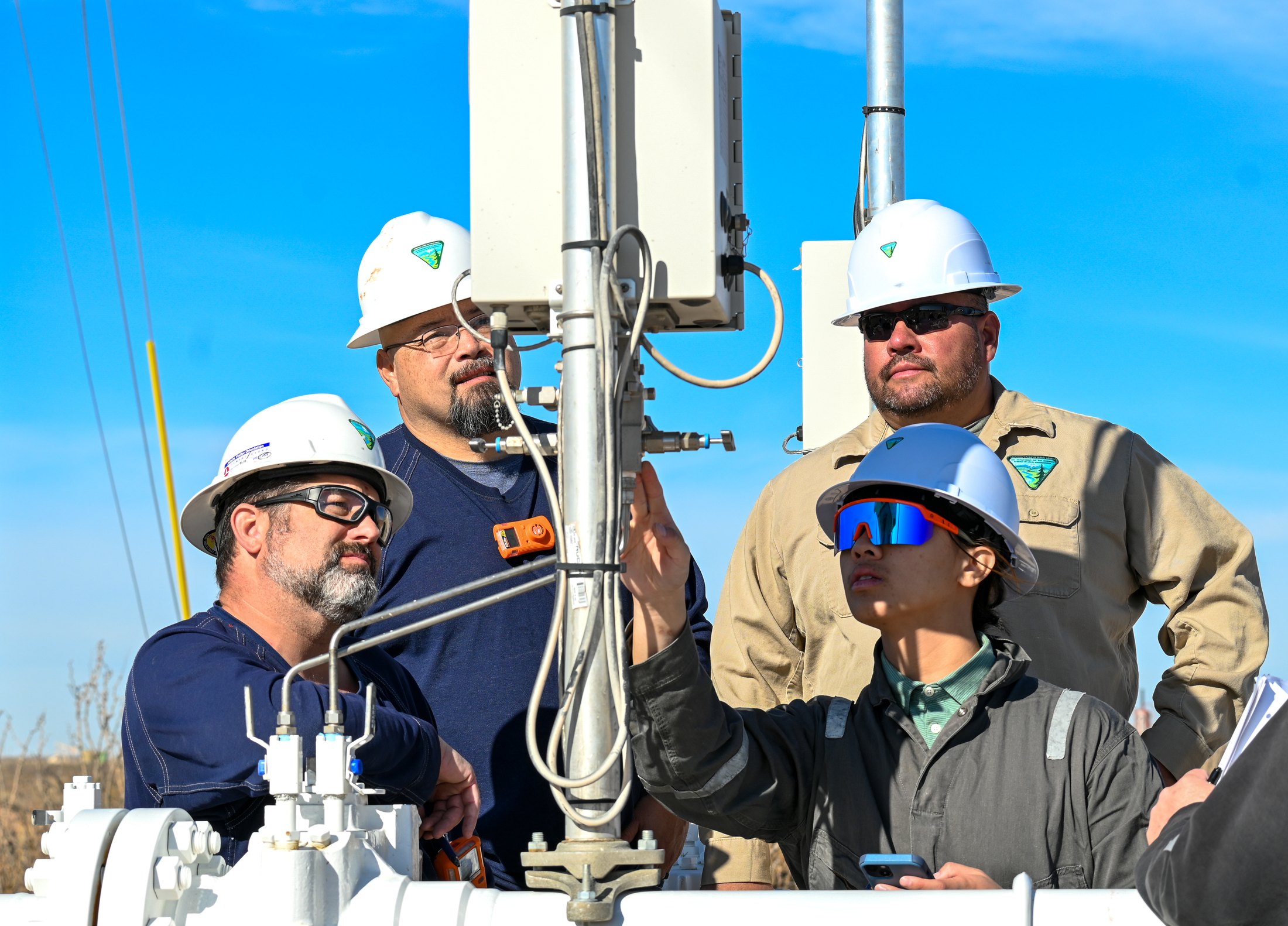 Four BLM petroleum engineering technicians inspect oil-field equipment near Hobbs, New Mexico.
