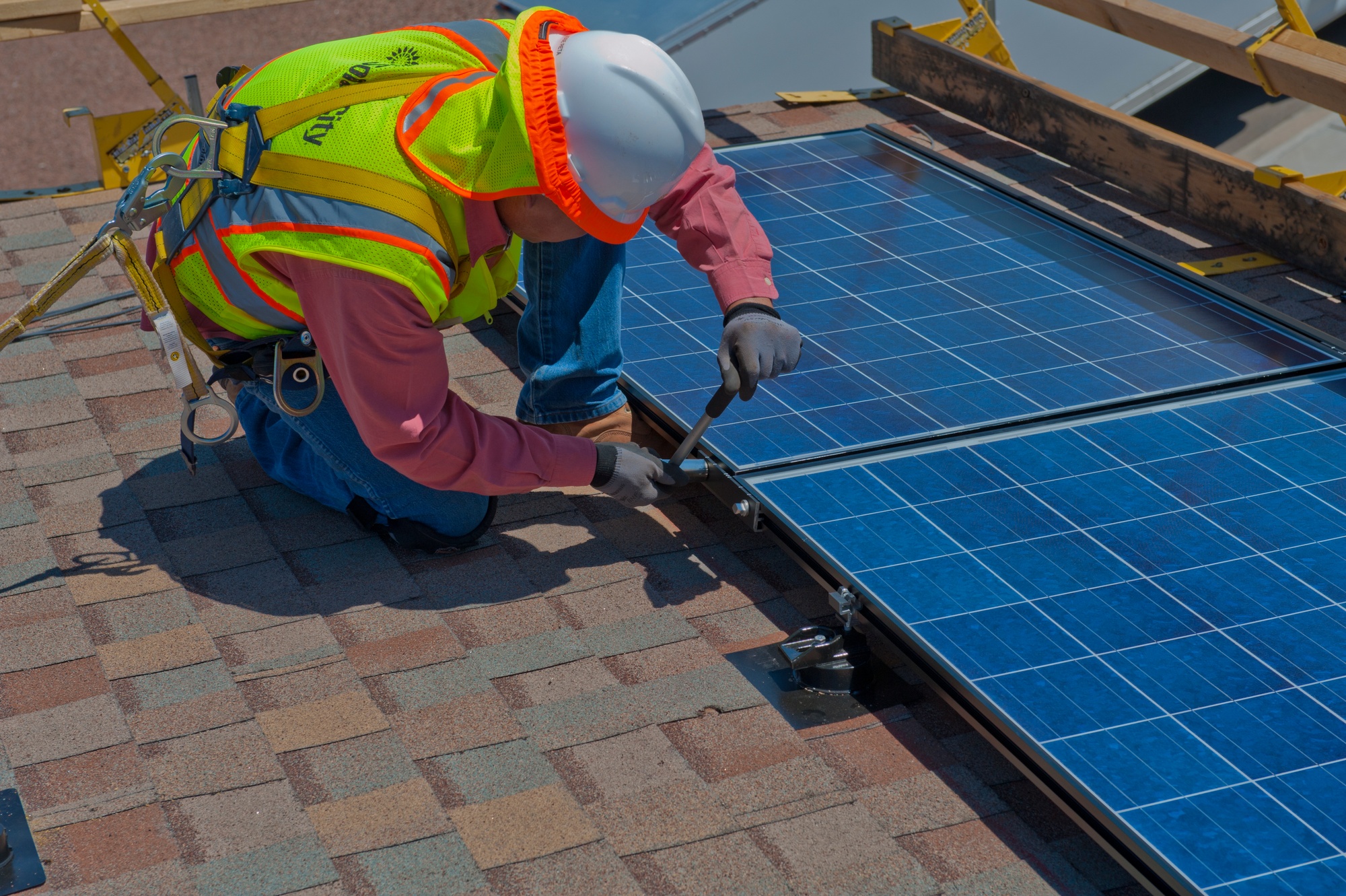 A contractor installing a rooftop solar panel at Holloman Air Force Base in Otero County.