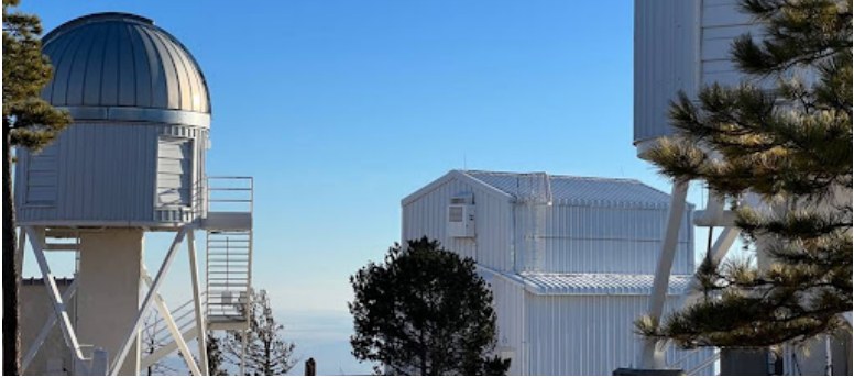 Astronomy buildings and an observatory dome among trees.