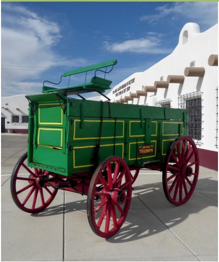 A historic green wagon displayed outdoors.